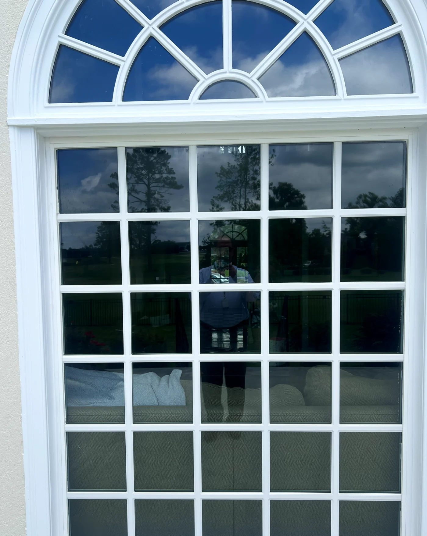 An arched wood window with a divided lite grid pattern set in a plaster wall