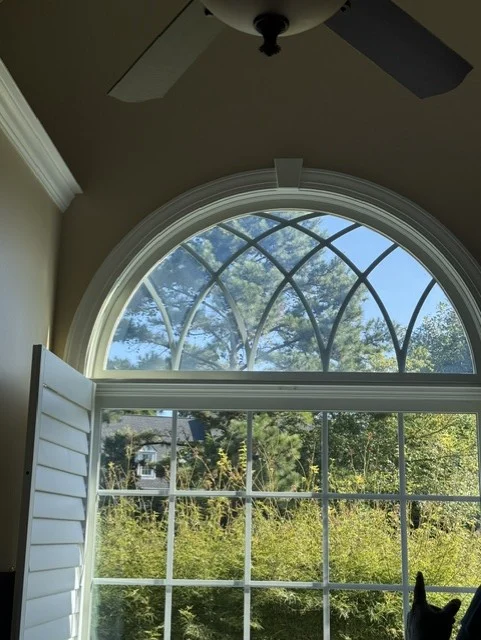 A radius head transom with a fan lite grid pattern above a divided lite wood window