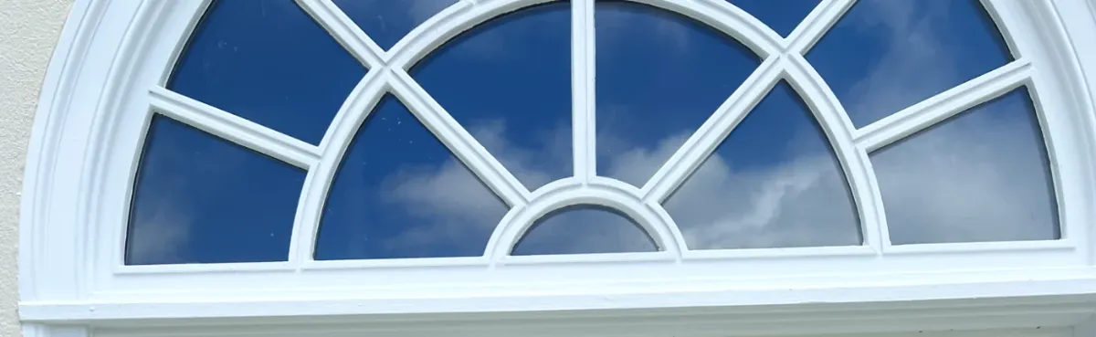 A Palladian wood window assembly with a radius head and divided lites above a finished room