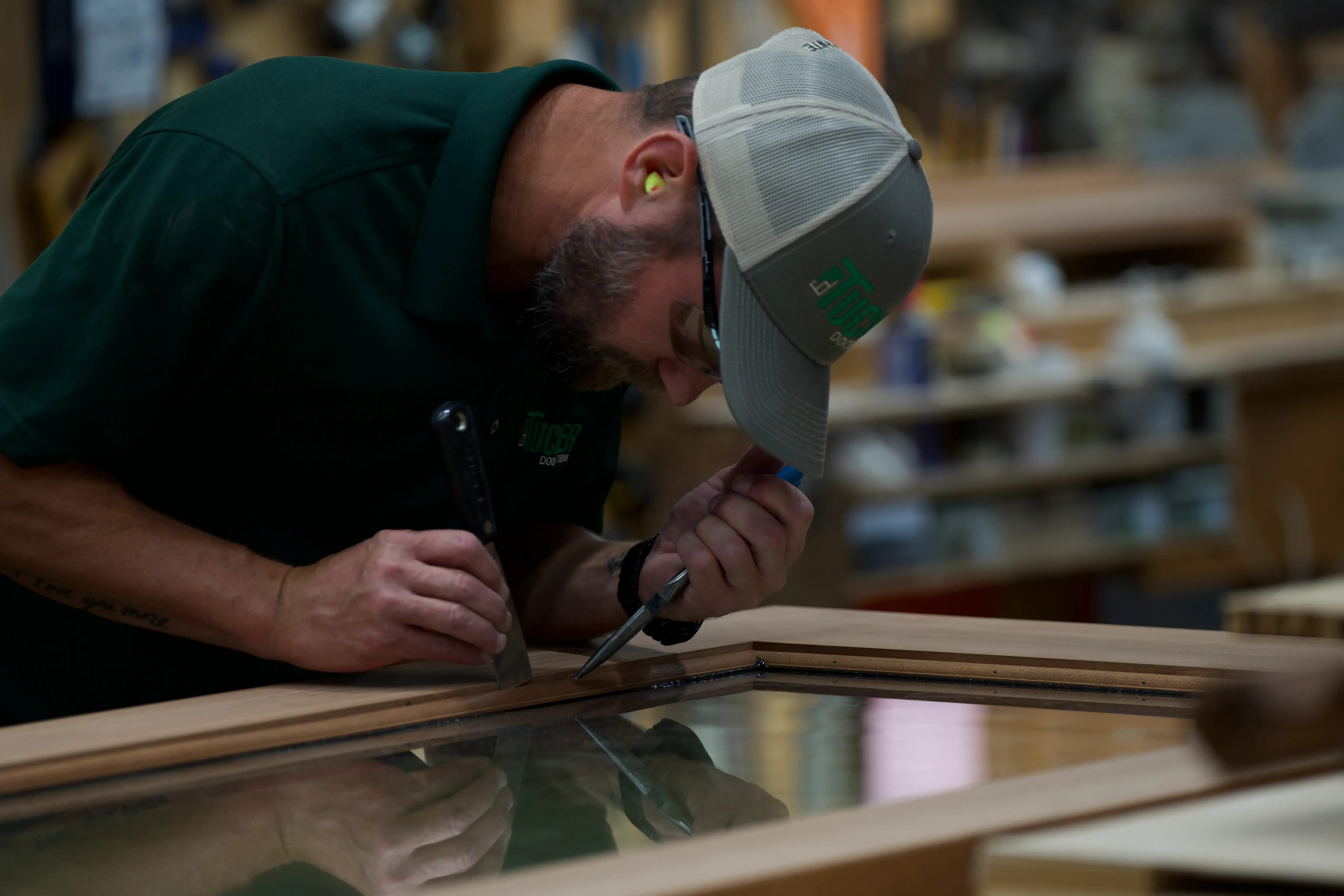 A Tucker craftsman fitting glass into a wood door at the bench