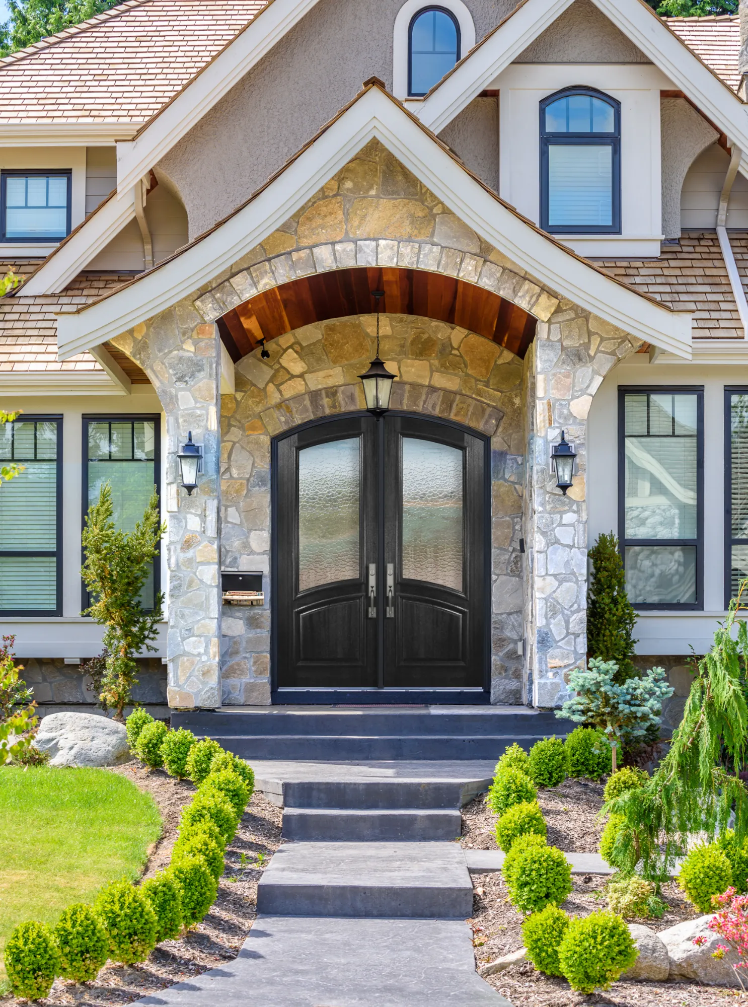 An arch-top mahogany double entry door under a stone archway