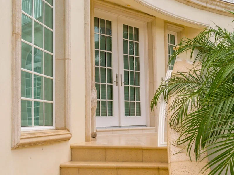 White Neuma french entry doors set in a stone facade