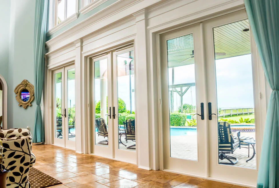 A run of white Neuma french doors with transoms opening onto a pool deck