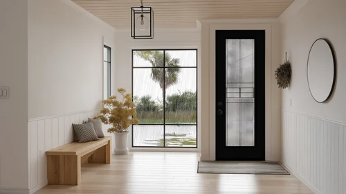 A white foyer with a black entry door glazed in patterned privacy glass