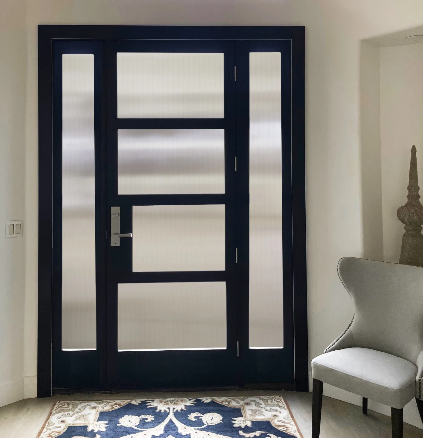 Black four-lite entry door with reeded glass and sidelites