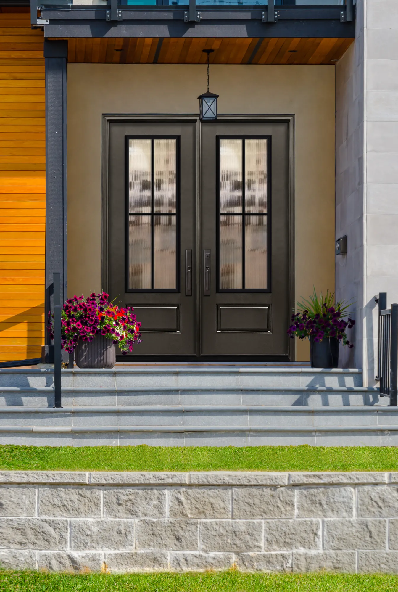 Bronze double entry doors with reeded glass on a modern porch