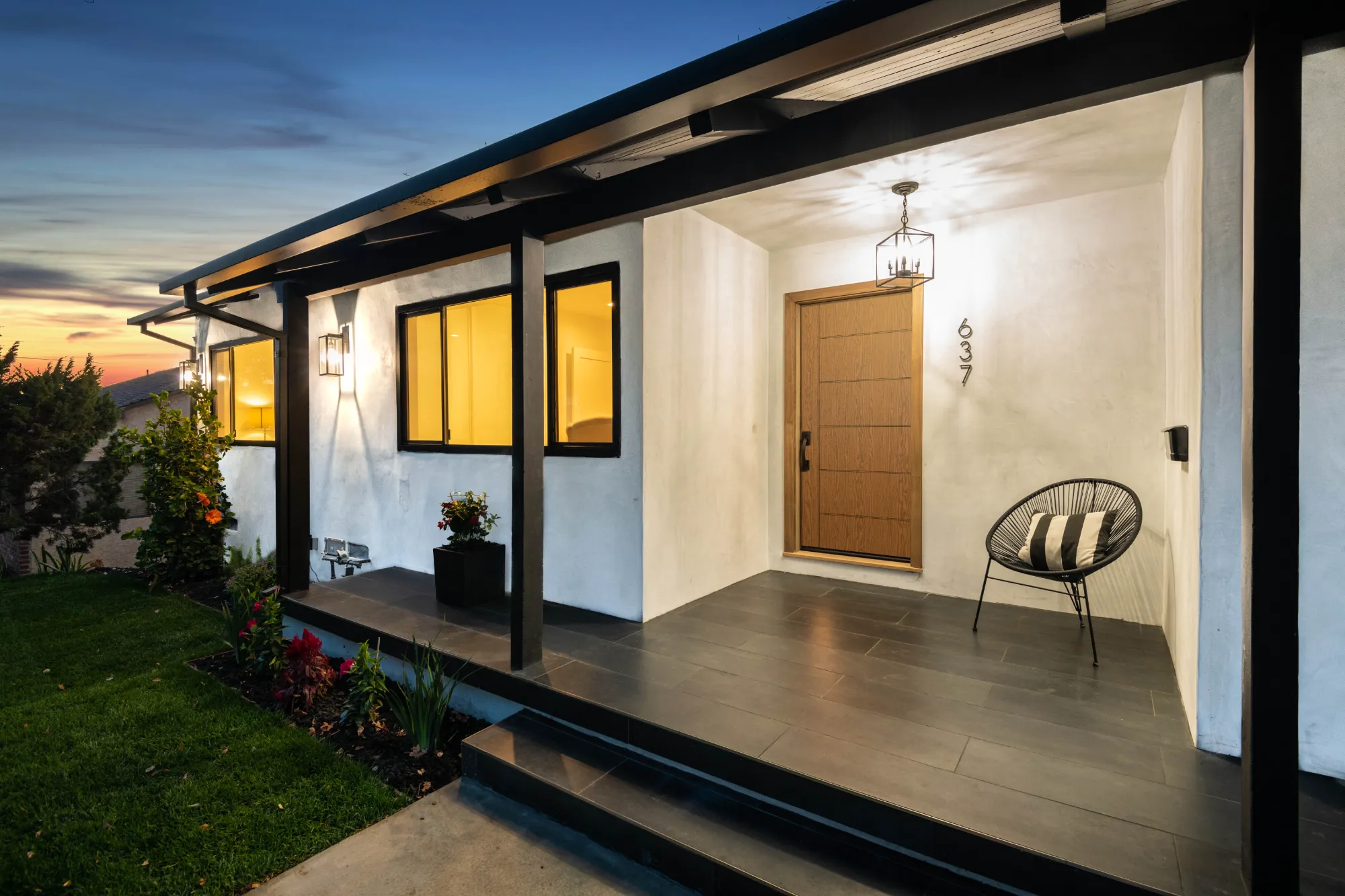 Oak plank fiberglass entry door on a modern porch at dusk