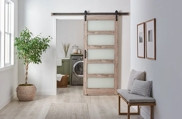 An ash grey five-lite barn door on black hardware at a laundry room