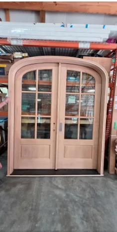 Unfinished knotty alder radius top double doors standing in the Tucker shop