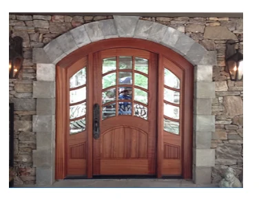 An arched mahogany entry with curved sidelites set in a stone opening