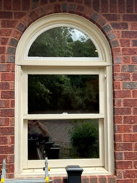 A new half round transom over a double hung in a brick arch opening