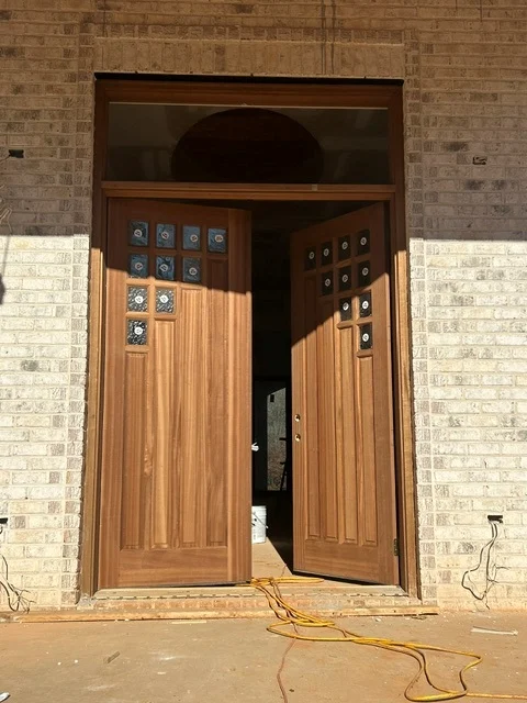 A mahogany double entry with speakeasy lites and a transom set in a brick opening