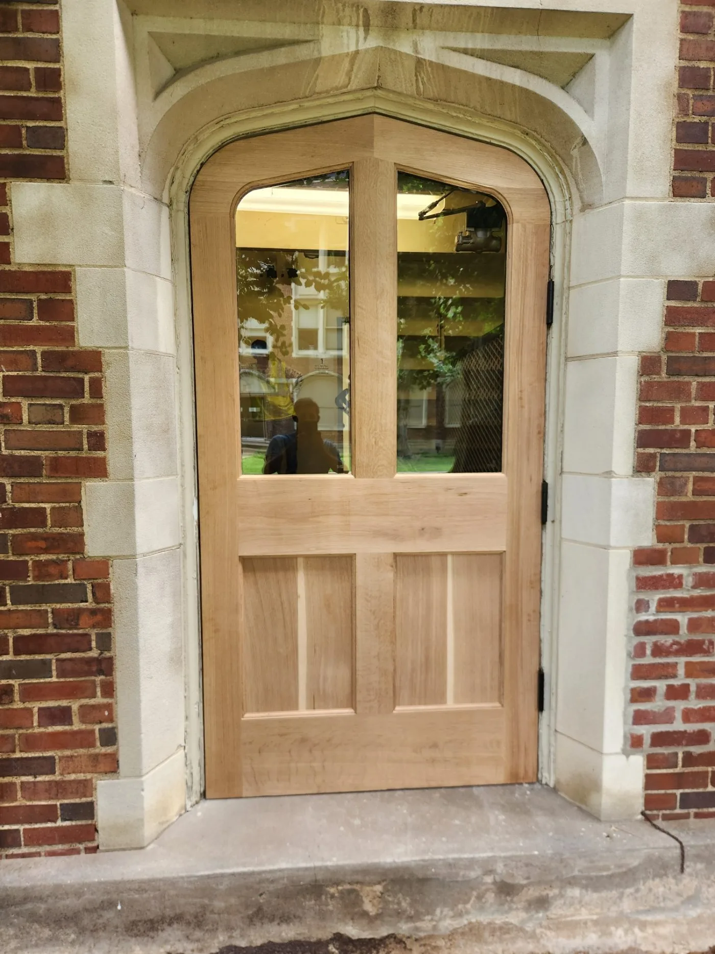 New white oak arched door hung in the stone opening