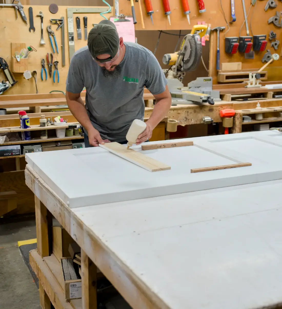 A Tucker craftsman gluing a stile onto a white door panel at the bench