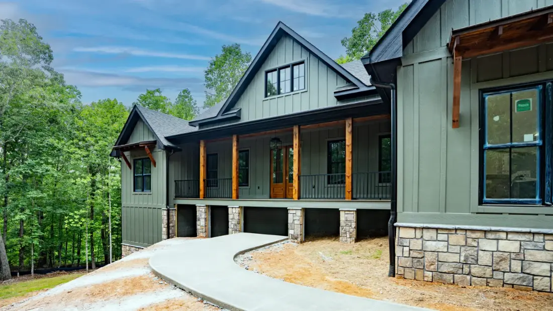 A green board and batten elevation with Tucker 3300 Series vinyl windows and a wood front entry door
