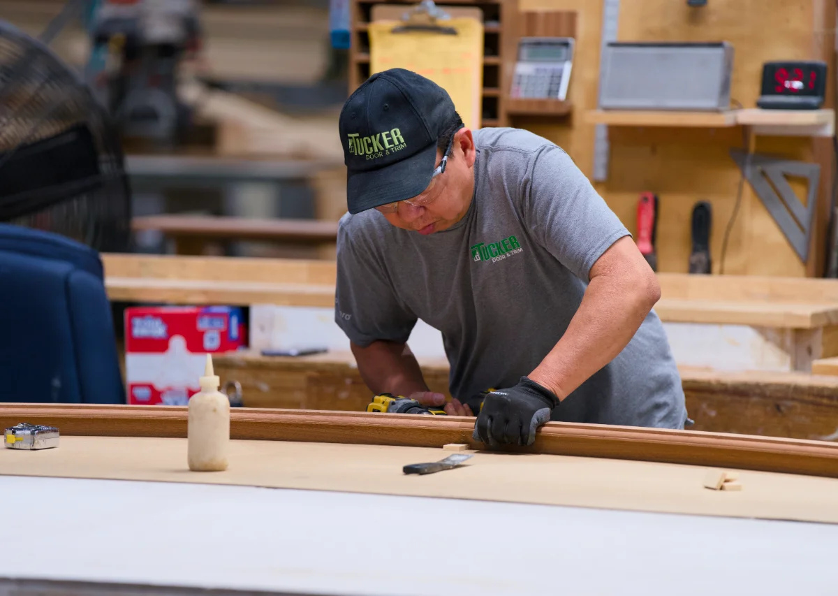 A Tucker craftsman fitting a curved rail onto a radius top door at the bench in Monroe, Georgia